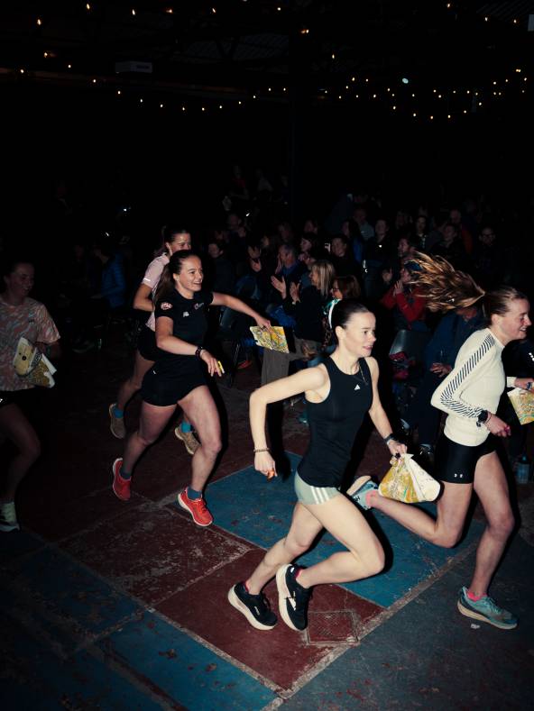 a group of young female orienteers are running through a crowd at the start of a race