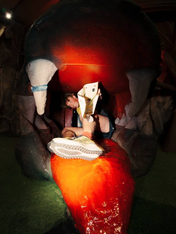 a male orienteer exits a dragon's mouth after punching an orienteering control